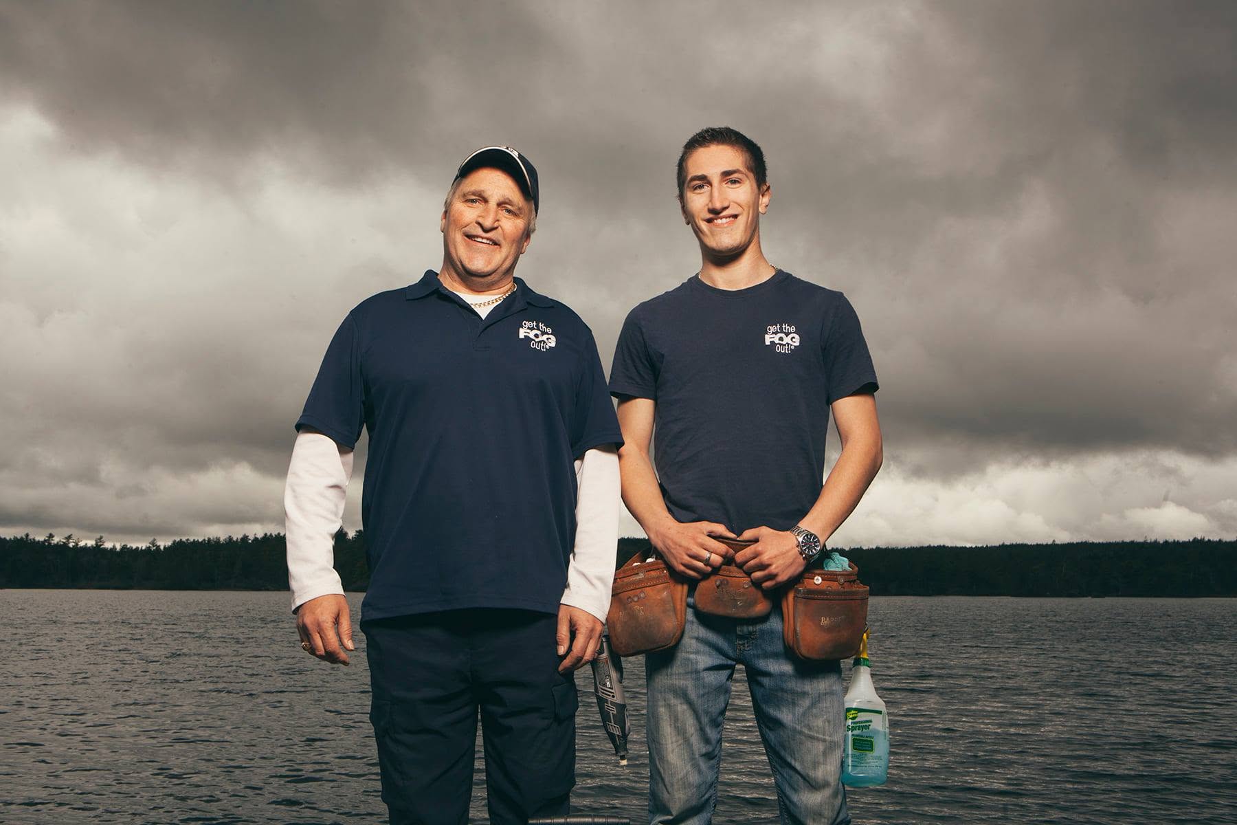 Mike and Kent Nugent in Get The FOG Out shirts with tool belts, by a lake in Nova Scotia.